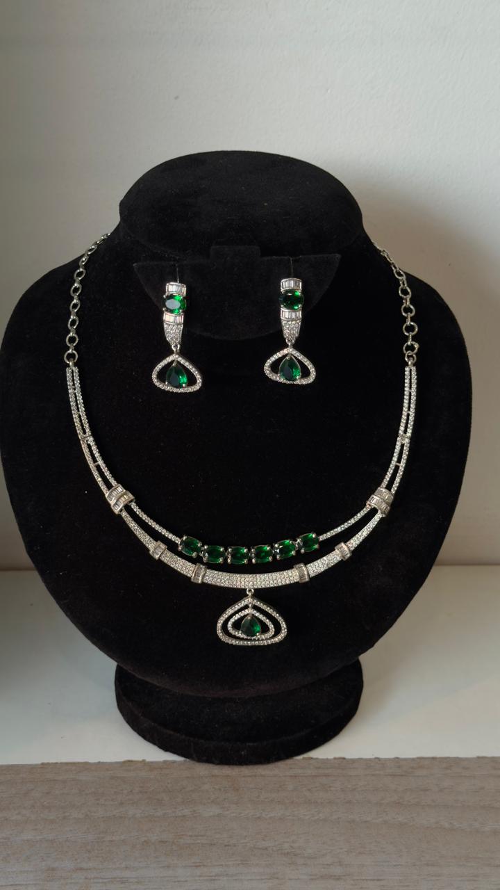Double layered silver-toned necklace accented with a row of vibrant emerald-green stones