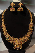 Traditional gold-tone temple jewellery set with a long necklace and matching jhumka earrings.
